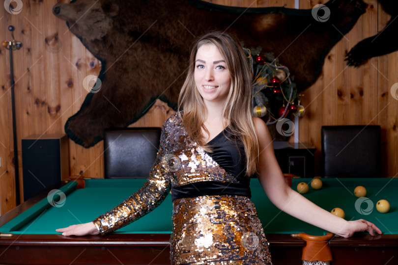 Скачать Женщина в черно-золотом платье стоит перед бильярдным столом фотосток Ozero