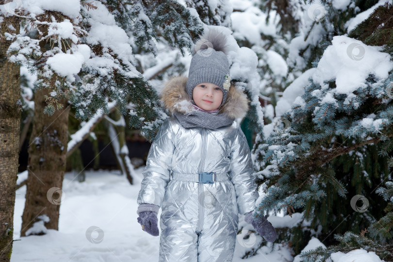 Скачать Молодая девушка в серебристом пальто и шляпке стоит на снегу фотосток Ozero