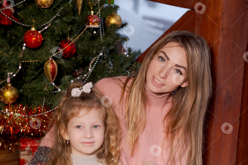 Скачать Женщина и маленькая девочка позируют перед рождественской елкой фотосток Ozero