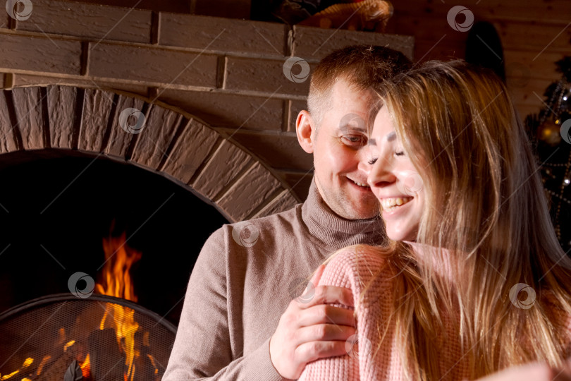 Скачать Мужчина и женщина обнимаются перед камином фотосток Ozero