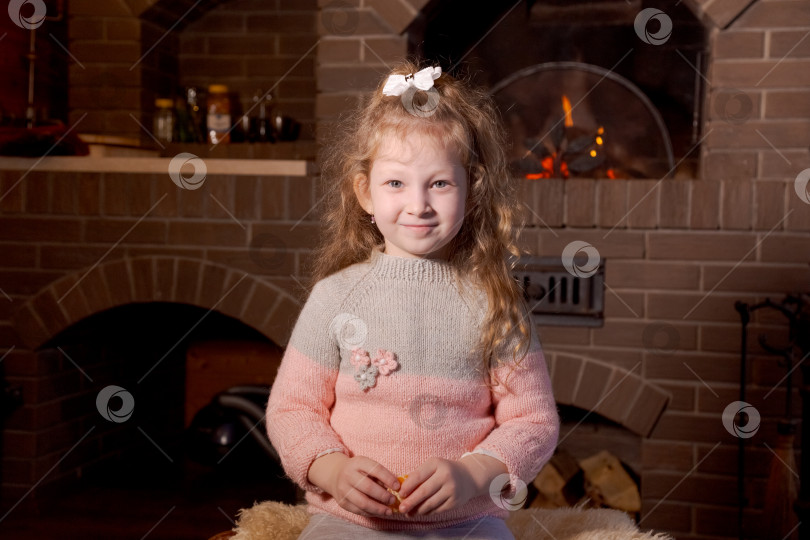 Скачать Маленькая девочка сидит на коврике перед камином фотосток Ozero