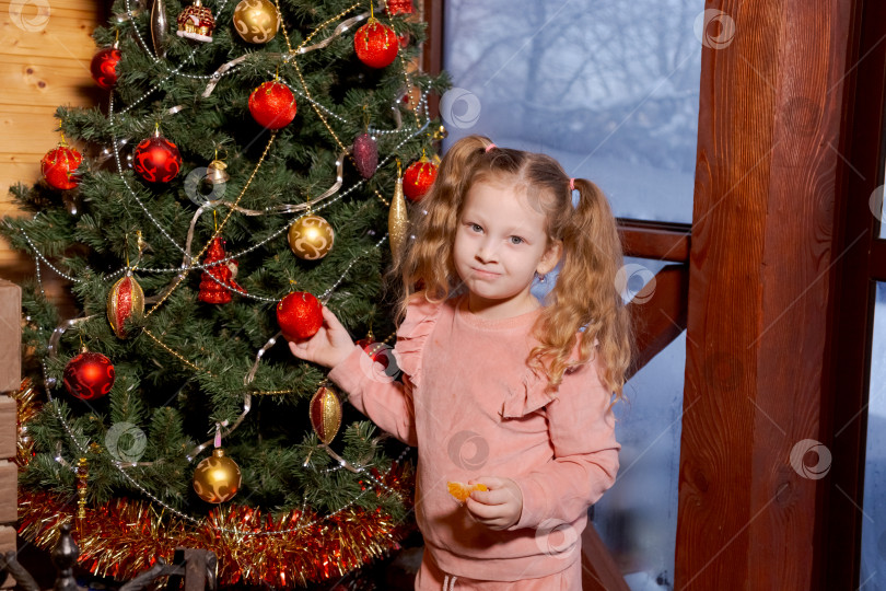 Скачать Маленькая девочка стоит перед рождественской елкой фотосток Ozero