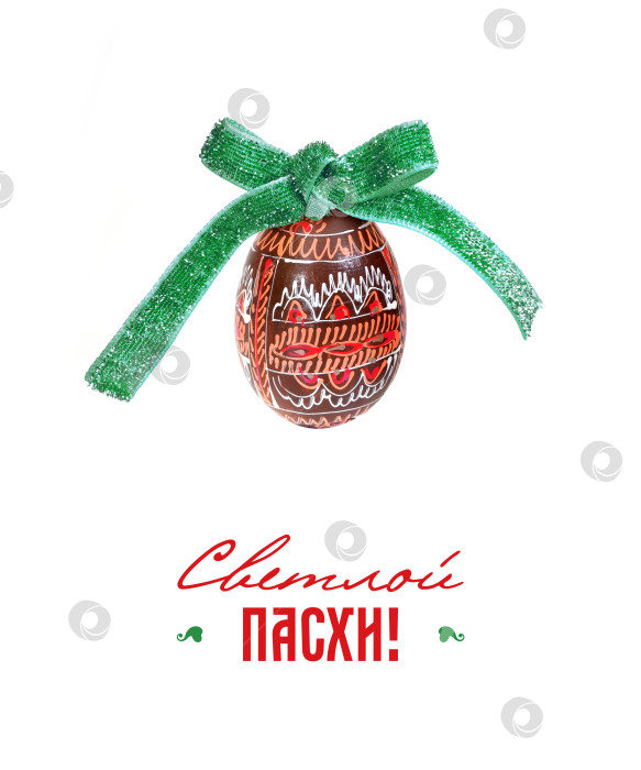 Скачать Украшенное пасхальное яйцо, перевязанное бирюзовой лентой, расположено в центре на простом белом фоне, передавая праздничное послание фотосток Ozero