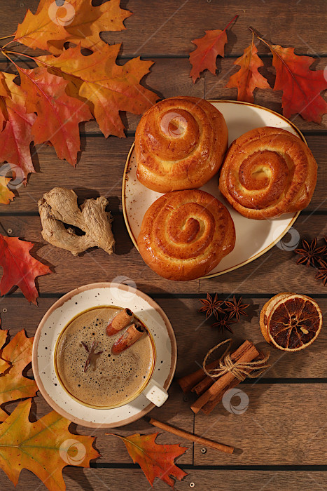 Скачать Булочки с корицей и горячим осенним напитком, кофейная глазурь и осенние опавшие листья, бадьян, имбирь и корица на деревянном столе, баннер для демонстрации, концепция осеннего поздравления, макет меню. фотосток Ozero
