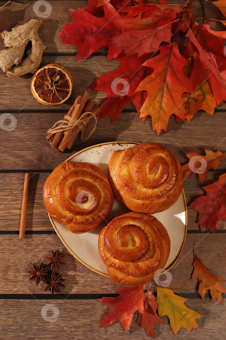 Скачать Булочки с корицей на деревянном столе с осенними опавшими листьями, звездчатым анисом, имбирем и корицей, баннер или шаблон витрины, концепция осеннего поздравления, макет меню и реклама пекарни. фотосток Ozero