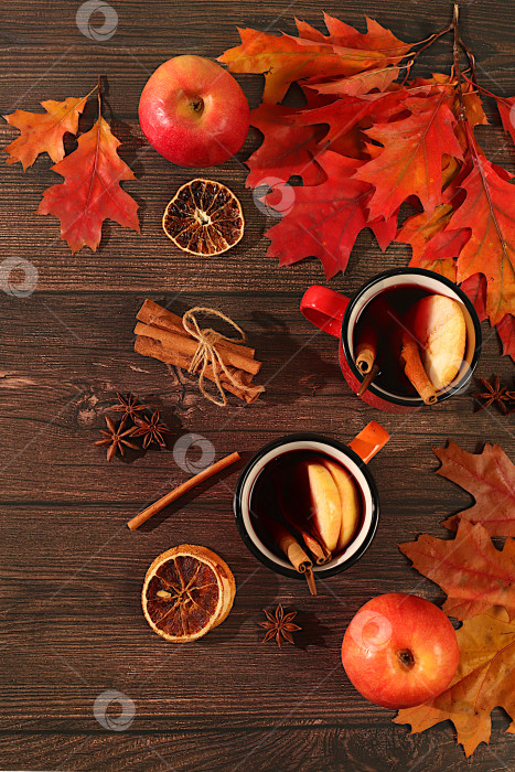 Скачать Две разноцветные эмалированные кружки с горячим осенним напитком, глинтвейн с яблоками и осенними опавшими листьями, бадьян, корица на деревянном столе, баннер для демонстрации, концепция осеннего поздравления, макет меню фотосток Ozero