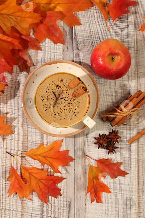 Скачать Индийский масала-чай с молоком, имбирем, анисом и корицей на старом деревянном столе с опавшими осенними листьями. Традиционный сезонный напиток со специями, рекламная открытка кафе, меню ресторана. фотосток Ozero