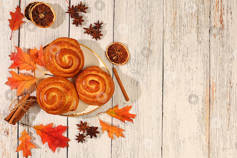 Скачать Булочки с корицей на деревянном столе с осенними опавшими листьями, звездчатым анисом, имбирем и корицей, баннер или шаблон витрины, концепция осеннего поздравления, макет меню и реклама пекарни. фотосток Ozero