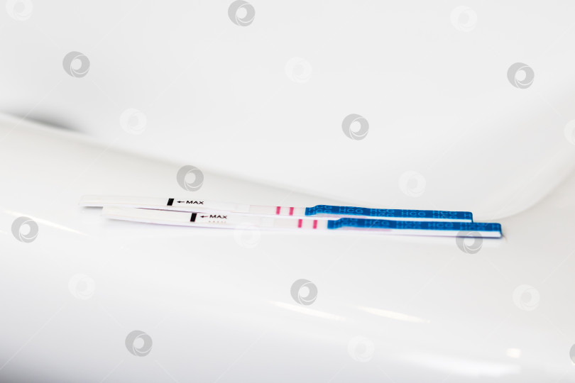 Скачать Набор тест-полосок на беременность, размещенных на чистой белой поверхности для использования и просмотра фотосток Ozero