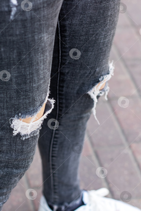 Скачать Потертые черные джинсы-скинни с рваными коленями и кроссовки - Городской стиль фотосток Ozero