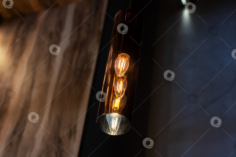 Скачать Подробное изображение крупным планом электрической лампочки, свисающей с потолка фотосток Ozero