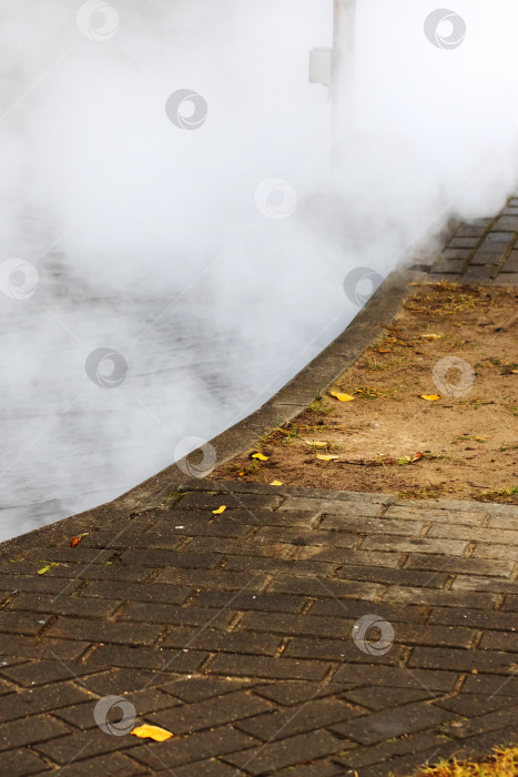 Скачать Изогнутая кирпичная дорожка с поднимающимся паром и осенними листьями фотосток Ozero