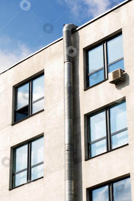 Скачать Фасад городского здания с металлическим вентиляционным каналом и окнами на фоне Голубого неба фотосток Ozero