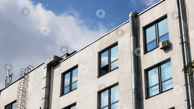 Скачать Высокое здание с многочисленными большими окнами, обрамленное ясным голубым небом фотосток Ozero