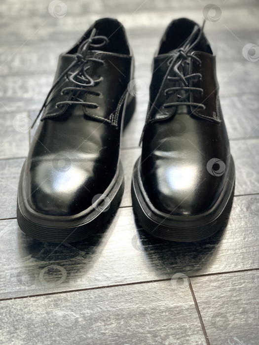 Скачать Черные кожаные туфли на деревянном полу, отражающая поверхность создает элегантный обувной фон фотосток Ozero