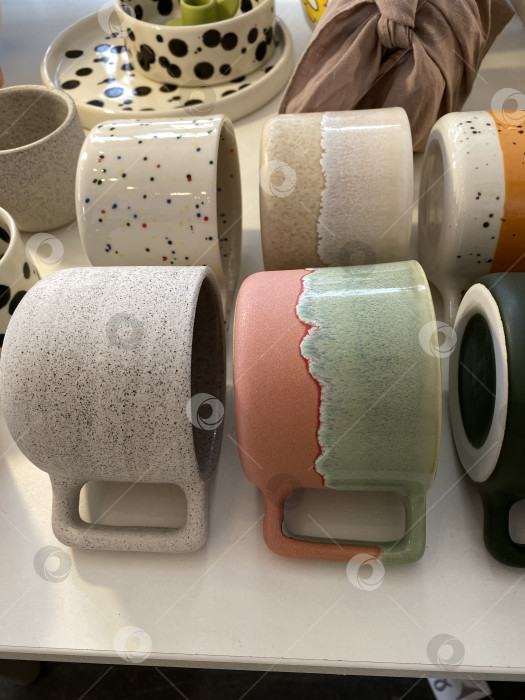 Скачать Красочные керамические кружки различного дизайна, выставленные на полке, идеально подходят для любителей домашнего декора фотосток Ozero