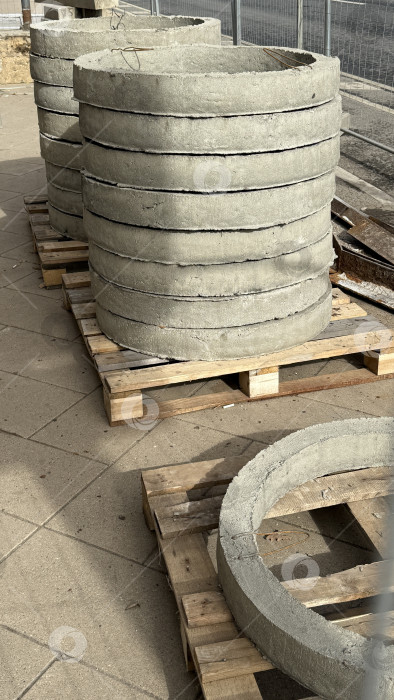 Скачать Бетонные кольца укладываются на деревянные поддоны на строительной площадке на открытом воздухе фотосток Ozero