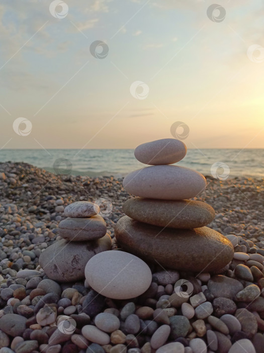 Скачать Сбалансированные каменные блоки в безмятежном стиле в серых и белых тонах, олицетворяющие спокойствие на фоне спокойного океанского заката фотосток Ozero