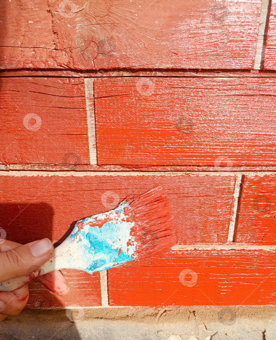 Скачать Рука с кистью наносит красную краску на деревянную поверхность, символизирующую самоделки и ремонт фотосток Ozero