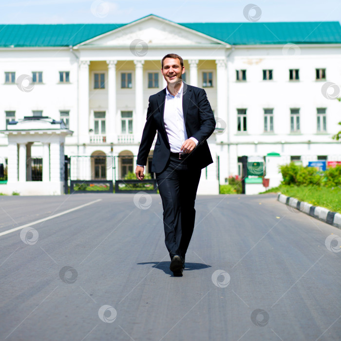 Скачать Портрет молодого бизнесмена в полный рост, идущего по дороге фотосток Ozero