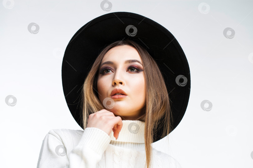 Скачать Портрет стильной молодой девушки в черной шляпке и белом свитере фотосток Ozero
