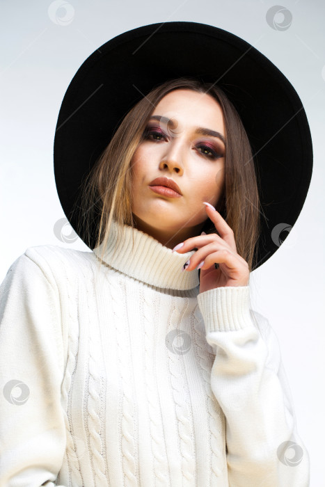 Скачать Портрет стильной молодой девушки в черной шляпке и белом свитере фотосток Ozero
