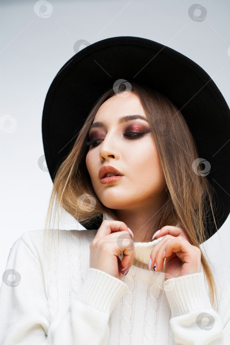 Скачать Портрет стильной молодой девушки в черной шляпке и белом свитере фотосток Ozero