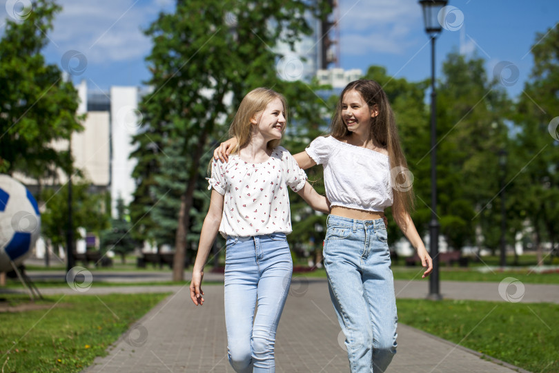 Скачать Две счастливые подружки-подростка прогуливаются по летнему парку. фотосток Ozero