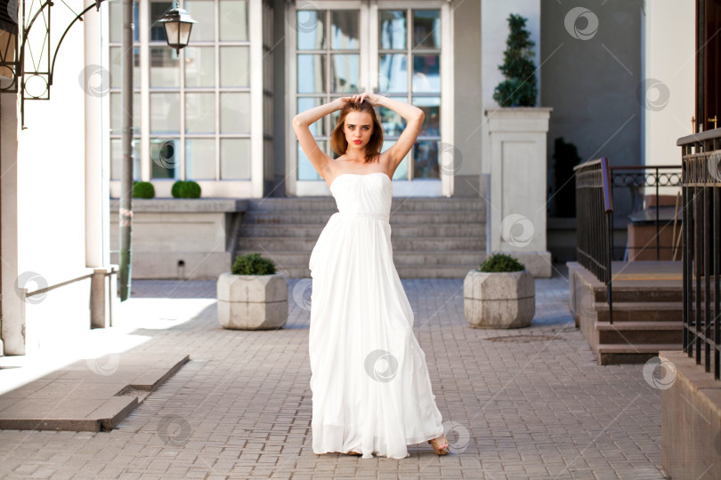 Скачать Портрет красивой женщины-модели в полный рост с длинными ногами, одетой в белое платье фотосток Ozero