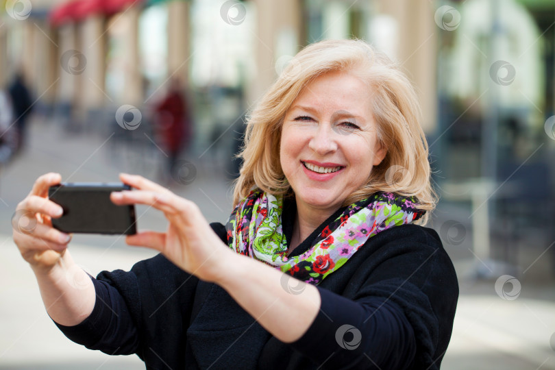 Скачать Счастливая зрелая красивая блондинка, сфотографированная на мобильный телефон на Спринг-стрит фотосток Ozero