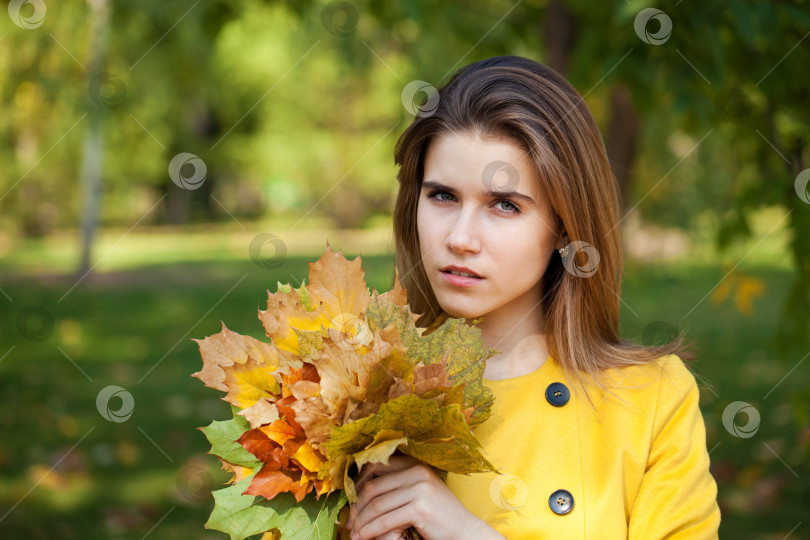 Скачать Счастливая молодая женщина в желтом пальто в осеннем парке фотосток Ozero