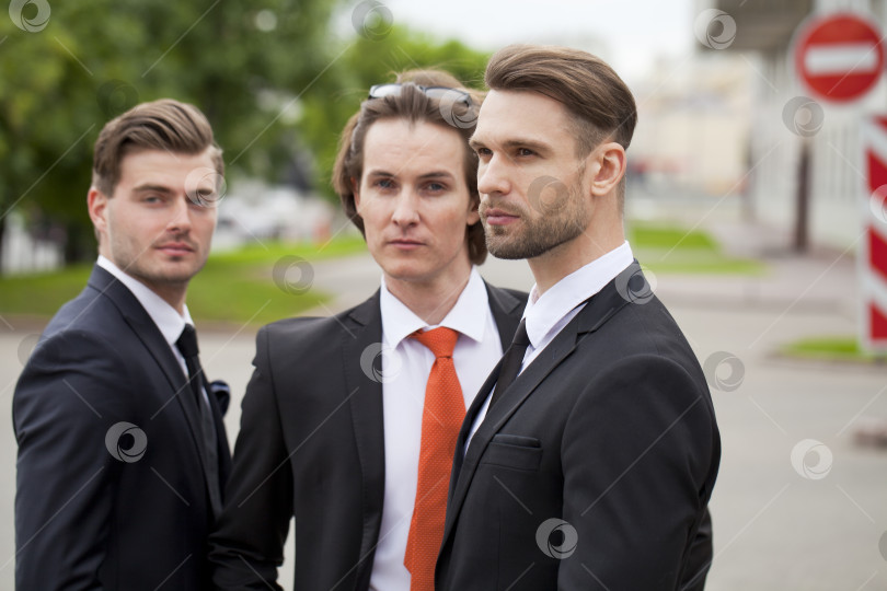 Скачать Трое молодых людей в элегантных деловых костюмах фотосток Ozero