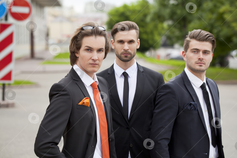 Скачать Трое молодых людей в элегантных деловых костюмах фотосток Ozero