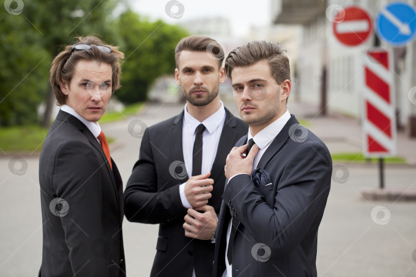 Скачать Трое молодых людей в элегантных деловых костюмах фотосток Ozero
