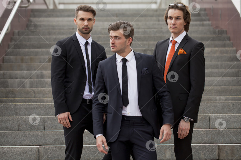 Скачать Трое молодых людей в элегантных деловых костюмах фотосток Ozero