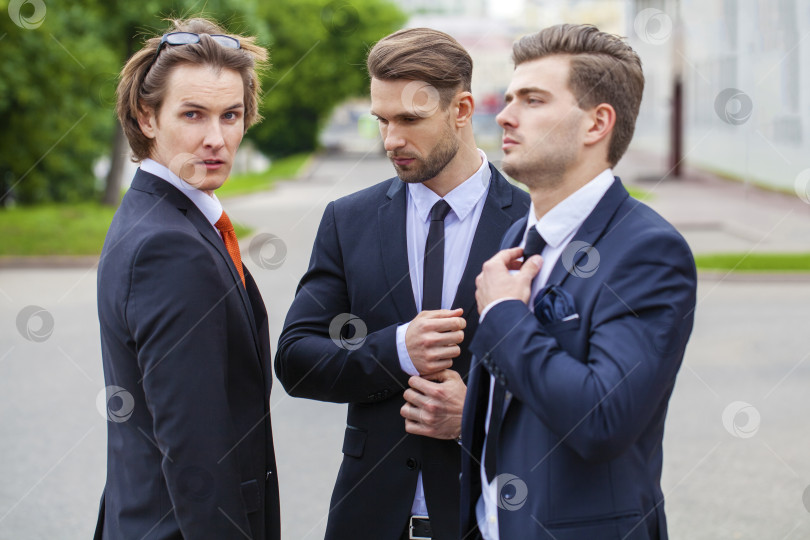 Скачать Трое молодых людей в элегантных деловых костюмах фотосток Ozero