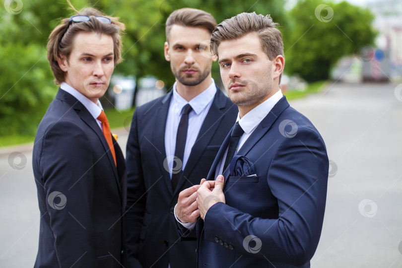 Скачать Трое молодых людей в элегантных деловых костюмах фотосток Ozero