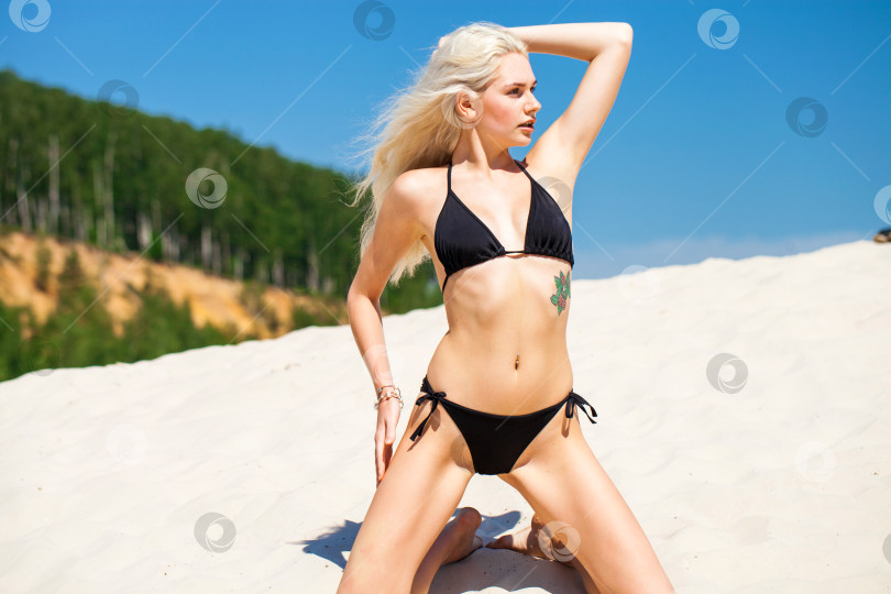Скачать молодая блондинка в черном бикини загорает на песчаном карьере фотосток Ozero