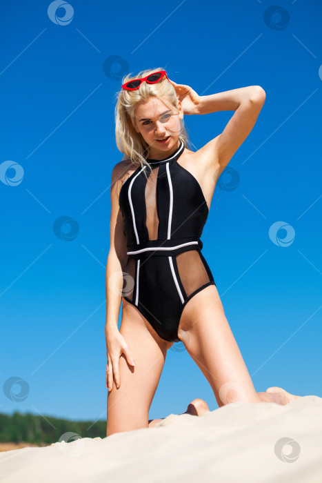 Скачать Молодая красивая женщина в черном бикини позирует на фоне песчаного карьера фотосток Ozero