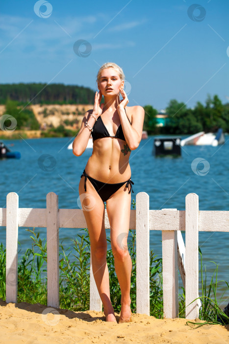 Скачать Молодая красивая девушка в однотонном черном купальнике позирует на пляже фотосток Ozero