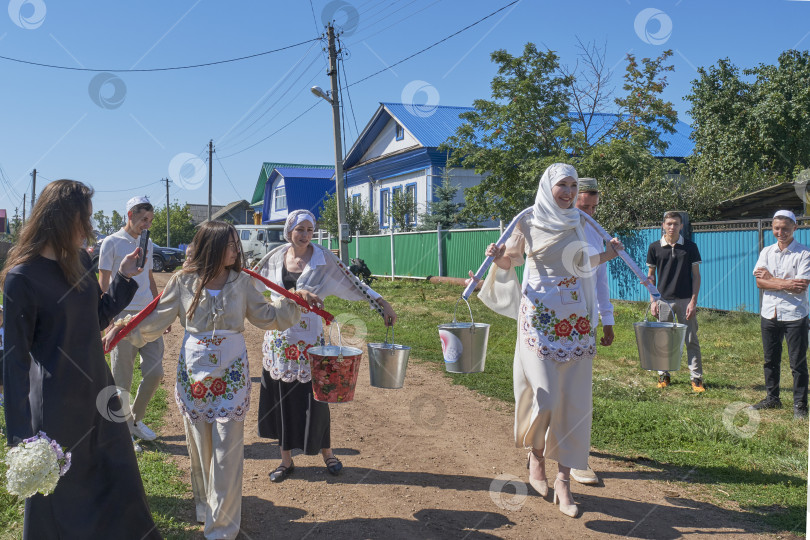 Скачать Татарская свадебная традиция в деревне. Невеста несет ведра с водой на коромысле фотосток Ozero