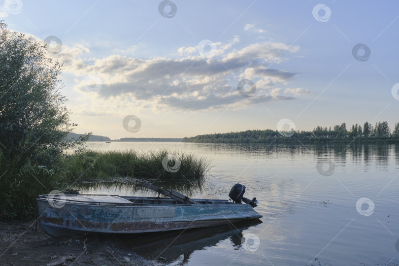 Скачать Старая рыбацкая лодка на берегу спокойной реки на закате фотосток Ozero