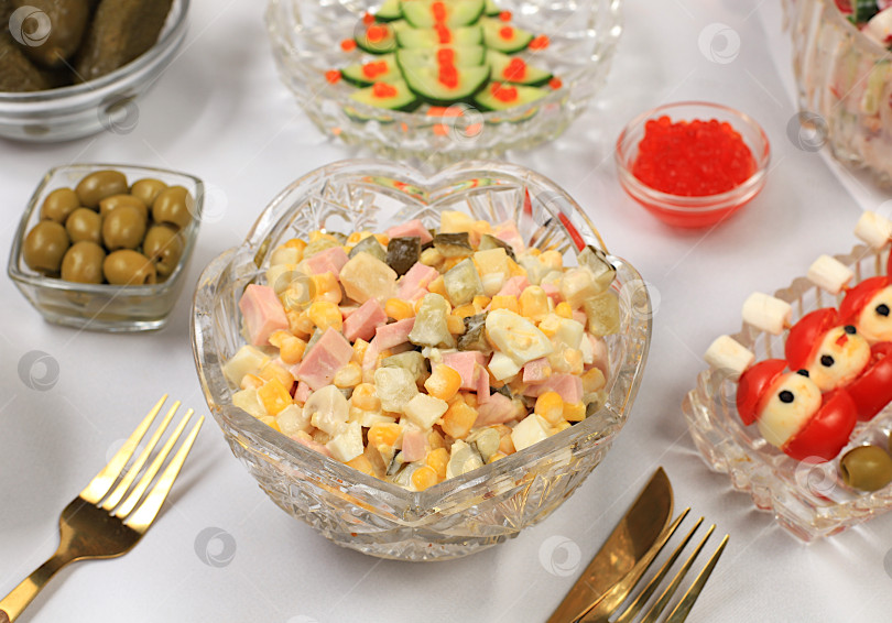 Скачать Праздничные рождественские и новогодние блюда на изысканном столе. Праздничный салат Оливье, салат из редиса и огурцов, маслины, красная икра, соленые огурцы и бокалы для шампанского. Концепция здорового образа жизни. фотосток Ozero