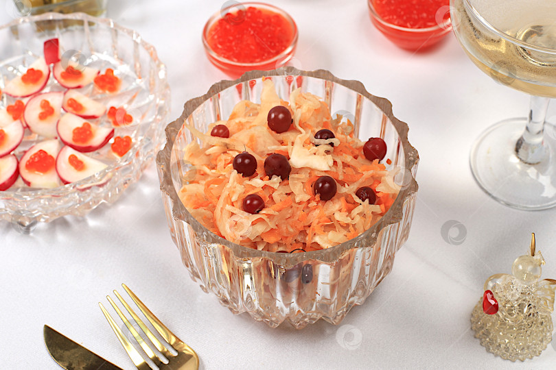 Скачать Праздничные рождественские и новогодние блюда на изысканном столе. Вегетарианские закуски из квашеной капусты с клюквой, редисом, огурцом, яйцом и оливковым салатом, красной икрой и бокалами шампанского — концепция здорового образа жизни. фотосток Ozero