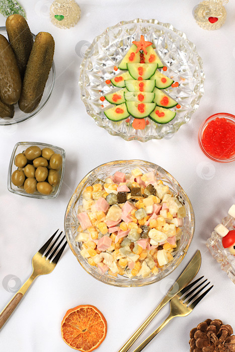 Скачать Праздничные рождественские и новогодние блюда на изысканном столе. Праздничный салат Оливье, салат из редиса и огурцов, маслины, красная икра, соленые огурцы и бокалы для шампанского. Концепция здорового образа жизни. фотосток Ozero
