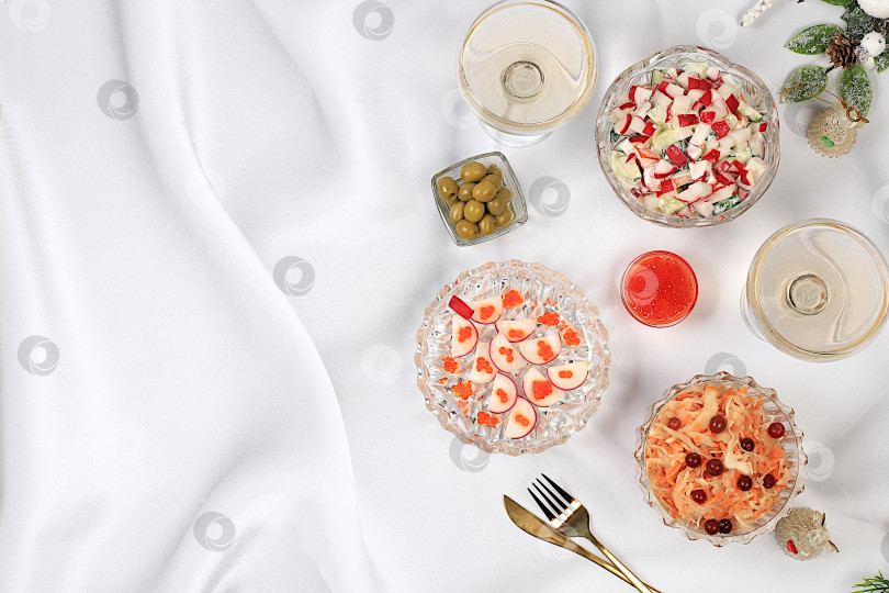 Скачать Праздничные рождественские и новогодние блюда на изысканном столе. Вегетарианские закуски из квашеной капусты с клюквой, редисом, огурцом, яйцом и оливковым салатом, красной икрой и бокалами шампанского — концепция здорового образа жизни. фотосток Ozero