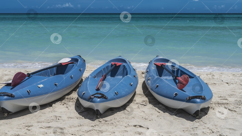 Скачать Три каноэ с веслами на песчаном пляже у аквамаринового океана фотосток Ozero