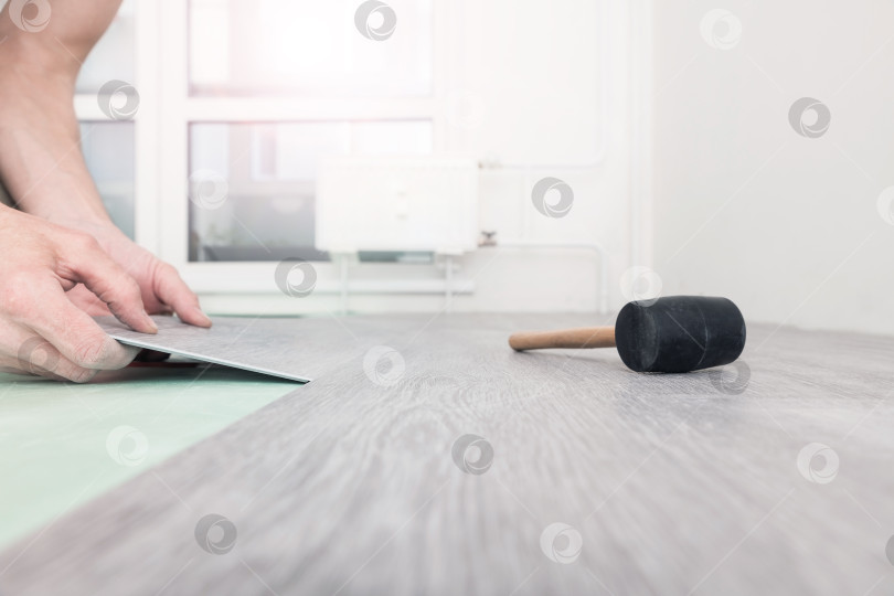 Скачать Мужчина кладет на пол кварцевый ламинат. фотосток Ozero