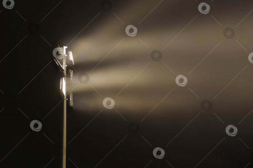 Скачать Прожектор, излучающий синий луч сквозь туманный воздух в темноте. фотосток Ozero