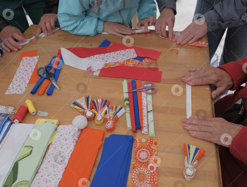 Скачать Руки, работающие над яркими тканевыми изделиями во время мастер-класса мансийских текстильных кукол фотосток Ozero